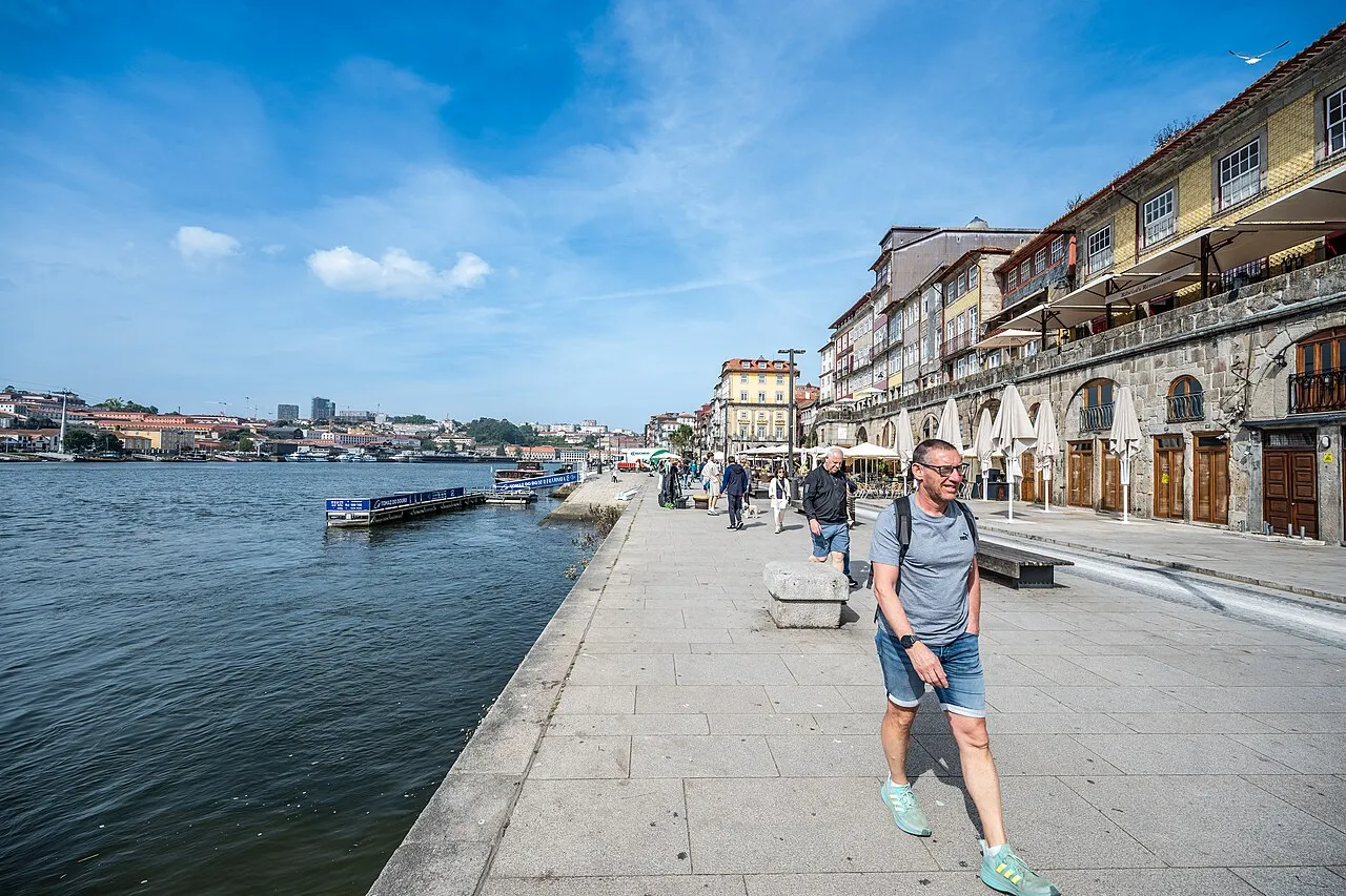 People walking along the Douro River waterfront in Porto, Portugal, with traditional buildings and boats visible. (55245783747)