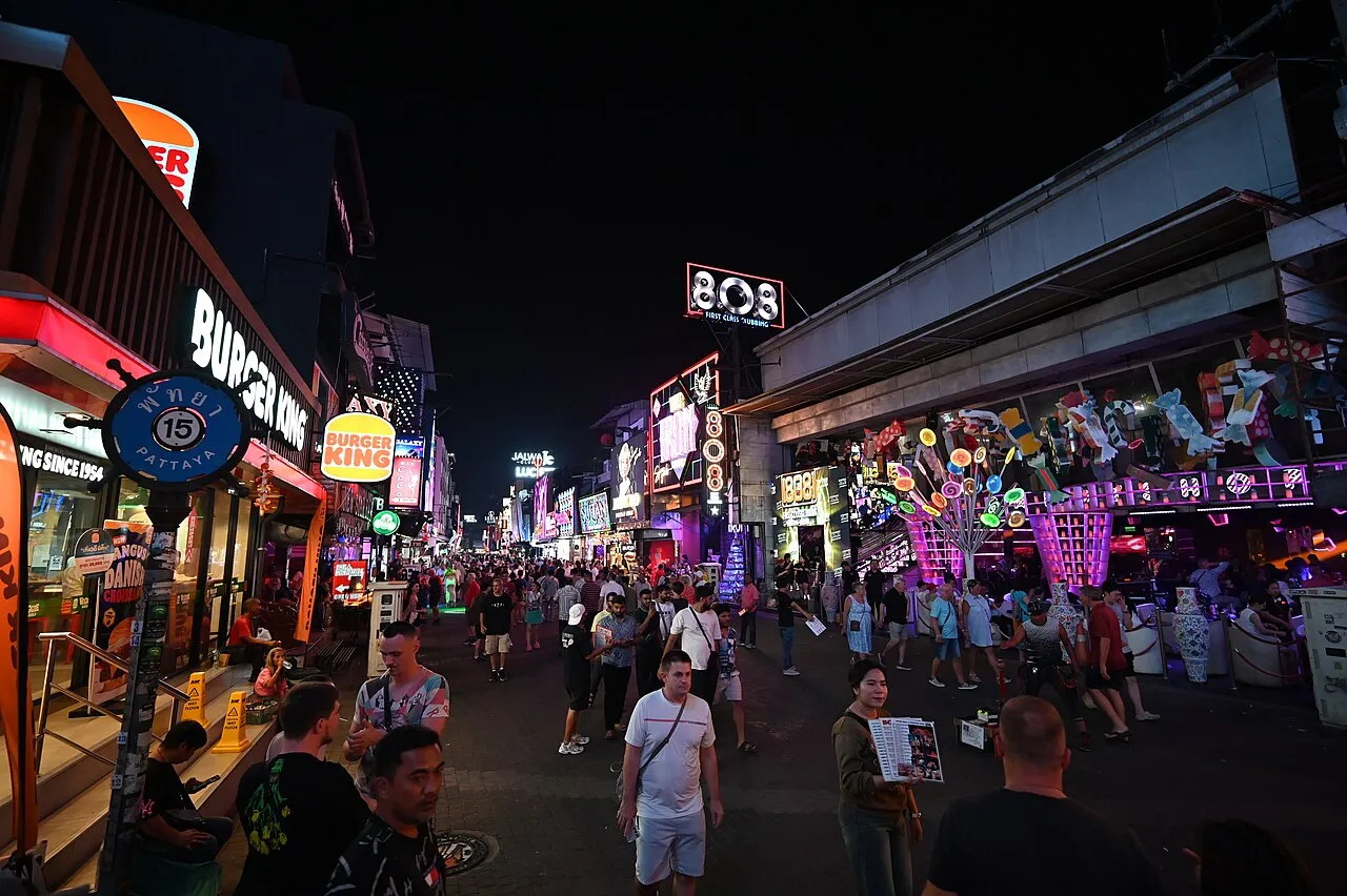 A neon-lit street of shopfronts and signs at night